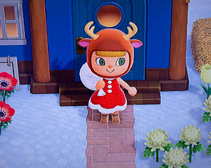 Screen short from Animal Crossing with character holding present bag and wearing reindeer hat.