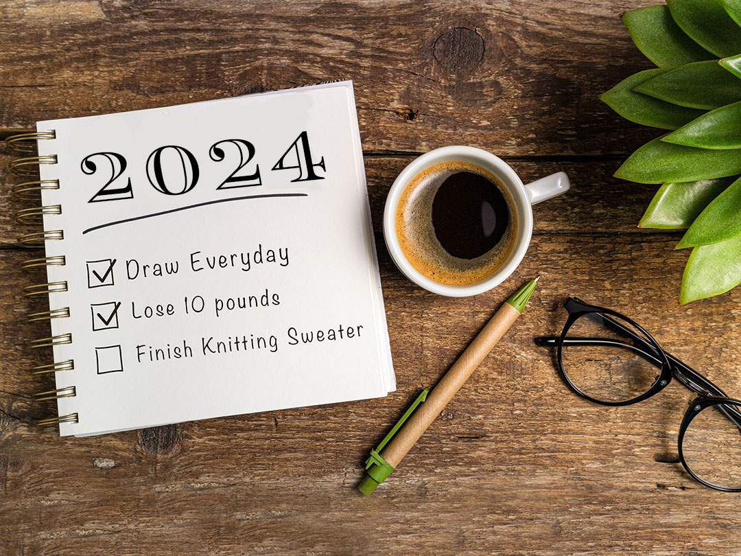 Checklist of goals for 2024 next to cup of coffee, pen and glasses.